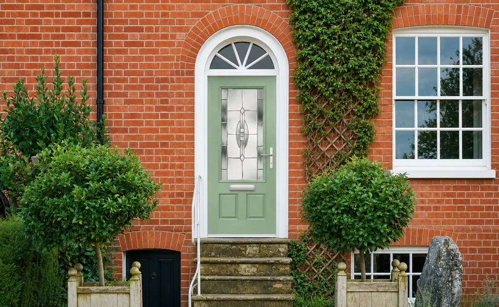 Light green composite front door on a traditional brick home in Aylesbury with decorative glazing and tidy entrance steps